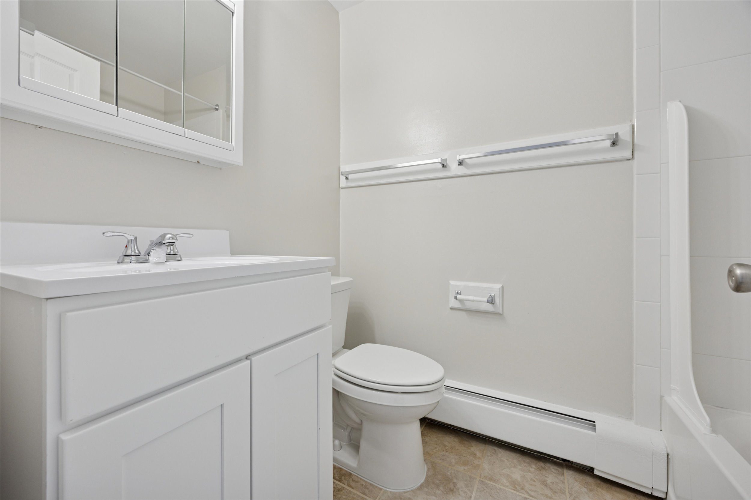 A white bathroom with a toilet, sink, and bathtub.
